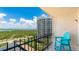 Balcony with a bright blue Adirondack chair overlooking lush tropical foliage and the ocean at 1212 Benjamin Franklin Dr # 909, Sarasota, FL 34236