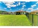 Wide-open backyard with lush green lawn, enclosed by a black metal fence, and a covered patio at 12815 24Th Street E Cir, Parrish, FL 34219