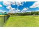 Spacious backyard with healthy green grass, black metal fence, and peaceful pond view in the distance at 12815 24Th Street E Cir, Parrish, FL 34219