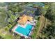 Aerial view of community pool with orange roofed building, palm trees, and tennis courts nearby at 12815 24Th Street E Cir, Parrish, FL 34219