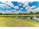Picturesque pond view featuring multiple homes on lush green lawns under a cloudy blue sky at 12815 24Th Street E Cir, Parrish, FL 34219