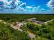 Wide aerial view showcasing homes surrounded by lush green trees, set against a blue sky with fluffy clouds at 1375 Norwalk Ter, Port Charlotte, FL 33953