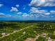 Wide aerial shot of a neighborhood nestled among lush green trees, with a clear sky and scattered clouds above at 1375 Norwalk Ter, Port Charlotte, FL 33953