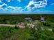 Wide aerial shot showcasing several homes surrounded by green trees, under a partly cloudy, vibrant blue sky at 1375 Norwalk Ter, Port Charlotte, FL 33953