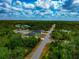 Scenic aerial view of homes along a road, surrounded by dense foliage, under a bright, partly cloudy sky at 1375 Norwalk Ter, Port Charlotte, FL 33953