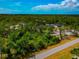 Aerial view featuring a home surrounded by lush trees, accompanied by RV parking and a vibrant blue sky at 1375 Norwalk Ter, Port Charlotte, FL 33953