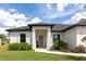 Inviting home featuring a manicured lawn, lush greenery, and a covered front porch at 1375 Norwalk Ter, Port Charlotte, FL 33953