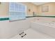 Clean bathroom featuring a large soaking tub, tile flooring, and a bright window, perfect for relaxation at 1526 Ewing St, Nokomis, FL 34275