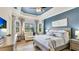 Relaxing bedroom features tray ceiling, calming blue accent wall, and plenty of natural light from large windows at 20359 Cristoforo Pl, Venice, FL 34293