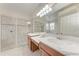 Bathroom featuring double sinks, a large mirror, a tiled shower with a glass door, and neutral countertops at 207 Winding River Trl, Bradenton, FL 34212