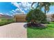 Charming home with a brick driveway, beautiful lawn, mature tree, and a two-car garage at 207 Winding River Trl, Bradenton, FL 34212