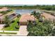 Beautiful front exterior with brick paver driveway, terra cotta roof, manicured lawn, and lake view in the back at 207 Winding River Trl, Bradenton, FL 34212