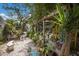Landscaped backyard with a wooden pergola, lush greenery, and bench seating at 2207 Hickory Ave, Sarasota, FL 34234