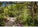Tranquil backyard retreat featuring lush plants, stone path, and shade trees at 2207 Hickory Ave, Sarasota, FL 34234