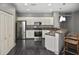 Open kitchen features white cabinets, stainless steel appliances, breakfast bar, and wood flooring at 2371 Manheim Ave, North Port, FL 34286