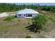 Aerial view of the modern home with a metal roof, expansive yard, and a covered back patio at 27510 67Th E Ave, Myakka City, FL 34251