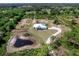 Expansive aerial view of a modern home on a large lot, complete with a serene pond and mature trees at 27510 67Th E Ave, Myakka City, FL 34251