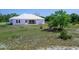 Backyard view of the modern white farmhouse and covered patio with a spacious lawn at 27510 67Th E Ave, Myakka City, FL 34251