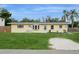 Quaint single-story home featuring a lush green lawn, mature landscaping, and a cozy entrance at 2804 W Mark Dr, Sarasota, FL 34232