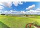 Expansive backyard with beautiful green grass, a serene pond, and colorful flowers in the foreground at 3518 Recurve Cir, Sarasota, FL 34240