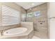 Luxurious bathroom showcasing a soaking tub, glass-enclosed shower, and tiled walls with a window at 3518 Recurve Cir, Sarasota, FL 34240