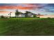 Beautiful single-story home with lush green lawn and tropical palm trees under a colorful sunset sky at 3518 Recurve Cir, Sarasota, FL 34240