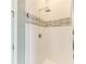 Modern shower featuring sleek white tiling, decorative mosaic trim, and a contemporary rainfall shower head at 3518 Recurve Cir, Sarasota, FL 34240