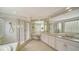 Bright bathroom featuring double vanity, soaking tub, glass block window, and glass-enclosed shower at 3521 Fair Oaks Ln, Longboat Key, FL 34228