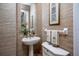 Charming powder room with pedestal sink, decorative mirror, and textured wallpaper at 3521 Fair Oaks Ln, Longboat Key, FL 34228
