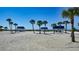 Beach features white pavillions with blue roofs with palm trees on a sunny day at 3521 Fair Oaks Ln, Longboat Key, FL 34228