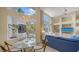 Bright living room with chandelier, large windows overlooking the pool, and comfortable blue seating at 3521 Fair Oaks Ln, Longboat Key, FL 34228