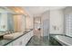 Spacious bathroom boasting dual sinks, white cabinetry, a soaking tub, and a glass block window for natural light at 3521 Fair Oaks Ln, Longboat Key, FL 34228