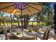 Outdoor dining area with an umbrella and seating, overlooking serene golf course views at 3521 Fair Oaks Ln, Longboat Key, FL 34228