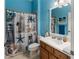 Bright blue bathroom featuring a seashell-themed shower curtain and a wood vanity with white countertop at 3740 Summerwind Cir, Bradenton, FL 34209