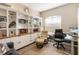 Bright home office featuring custom built-in shelving, wood floors, and comfortable seating area at 3740 Summerwind Cir, Bradenton, FL 34209