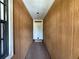 Hallway view showcasing wood paneled walls, with a white front door at the end, and a window to the left at 3957 Bearded Oaks Ct, Sarasota, FL 34232