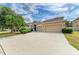 A three-car garage compliments a tan two-story home with trimmed bushes and mature palm trees decorating the expansive driveway at 4211 30Th E Ln, Bradenton, FL 34208