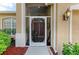A bright front porch featuring double wooden doors is adorned with lush plants in a decorative, tan home at 4211 30Th E Ln, Bradenton, FL 34208