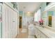 Bright bathroom featuring dual sinks, a soaking tub with shower, linen closet, and calming blue walls at 4211 30Th E Ln, Bradenton, FL 34208