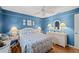 Bright blue bedroom with white wicker furniture, ceiling fan, and decorative finishes at 490 Pine Lily Way, Venice, FL 34293