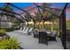 Enclosed patio features outdoor dining and lounge seating overlooking picturesque landscaping at 490 Pine Lily Way, Venice, FL 34293