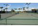 Well-maintained tennis court with lush green landscaping, shaded seating, and clear blue skies at 5330 Hyland Hills Ave # 2314, Sarasota, FL 34241