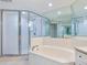 Bathroom featuring a glass-enclosed shower, a soaking tub, and bright tile flooring at 5430 Eagles Point Cir # 101, Sarasota, FL 34231