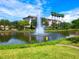 Scenic view of a pond with a fountain in front of a multi-story condo building under a blue sky at 5430 Eagles Point Cir # 101, Sarasota, FL 34231