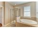 Bright bathroom featuring a glass shower and luxurious soaking tub under a window with plantation shutters at 5439 74Th E Pl, Ellenton, FL 34222