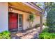 Inviting covered entrance features brick pavers, vibrant red door, and adjacent mature landscaping at 6412 Sun Eagle Ln, Bradenton, FL 34210