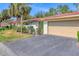 Villa featuring manicured greenery, a terra cotta roof, and an attached two-car garage at 6412 Sun Eagle Ln, Bradenton, FL 34210