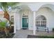 Inviting entrance with a green front door, tiled porch, white columns, and lush landscaping at 7424 Arrowhead Run, Lakewood Ranch, FL 34202