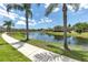 Scenic view of a community pond with a fountain, framed by palm trees and lush greenery at 7593 Plantation Cir, Bradenton, FL 34201