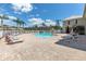 Community pool with lounge chairs, palm trees, and a seating area at 7593 Plantation Cir, Bradenton, FL 34201